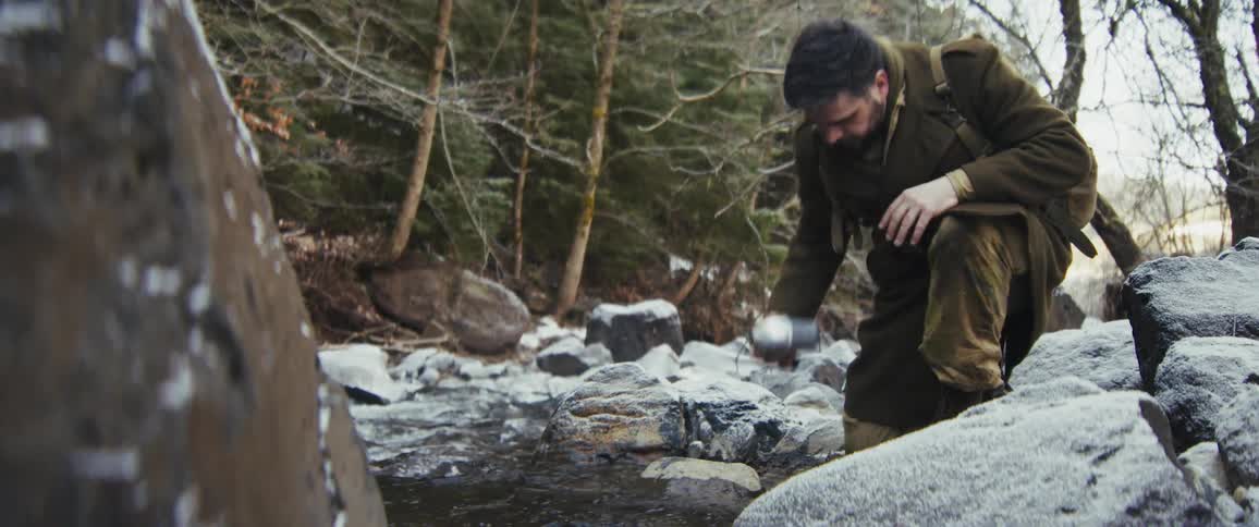 The hiker fills his canteen at the stream