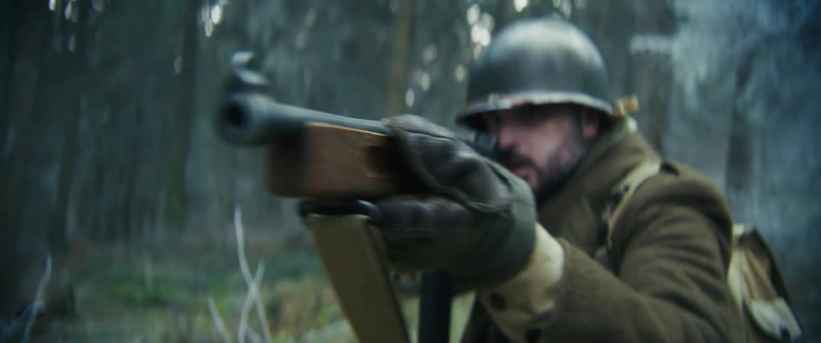 Soldier in the middle of the snowy forest pointing his rifle