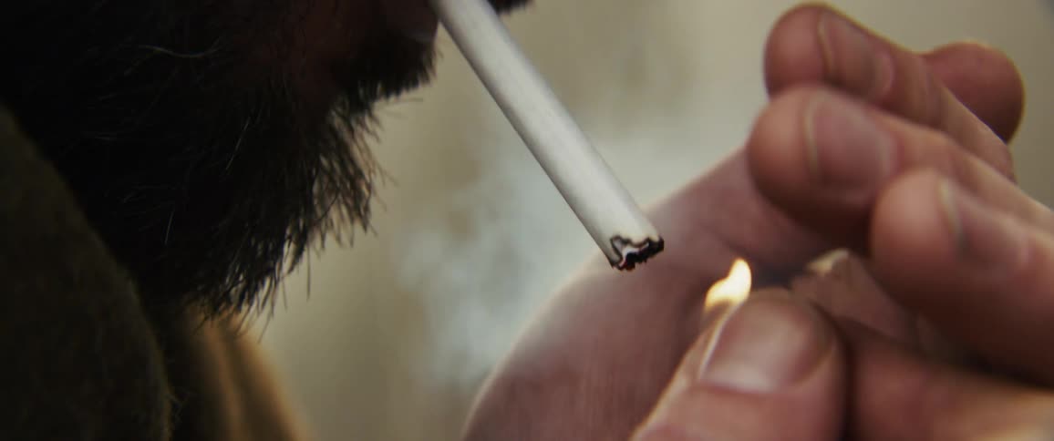 The man lights a cigarette and smokes