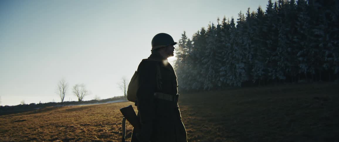 A soldier standing outdoors in a field