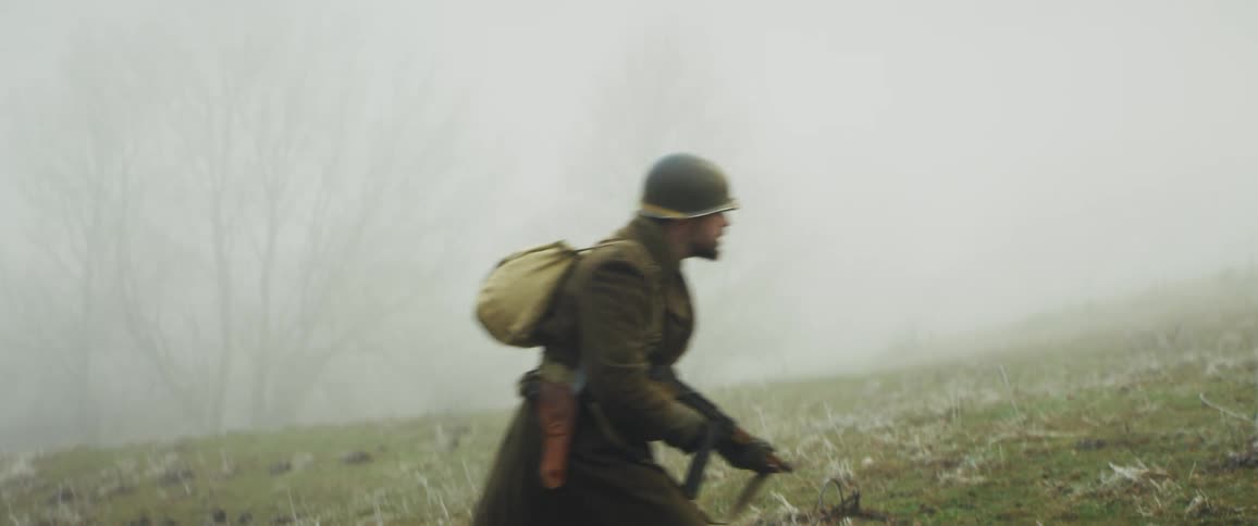 A soldier with a gun walking through a field