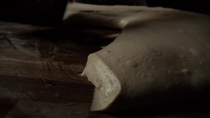 A person rolling dough on a table