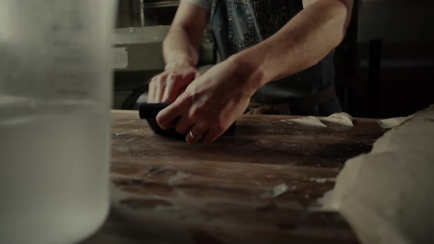 The cook is making balls of dough in the kitchen