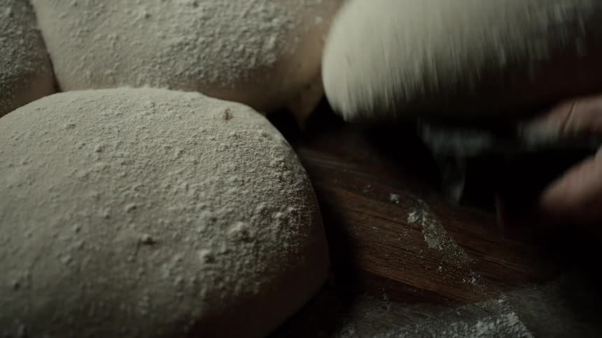 Baker cuts bread dough on a table in the kitchen