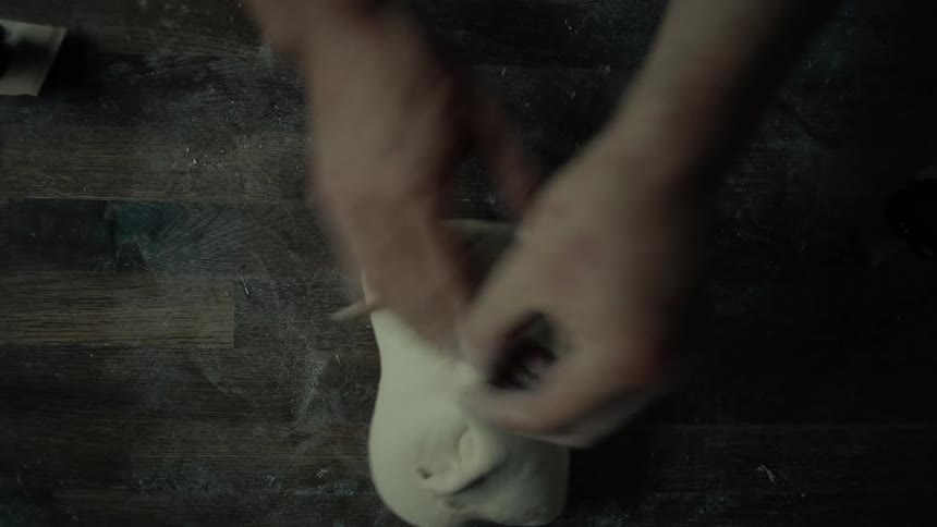 A chef molding dough into a smooth round shape preparing it for the oven