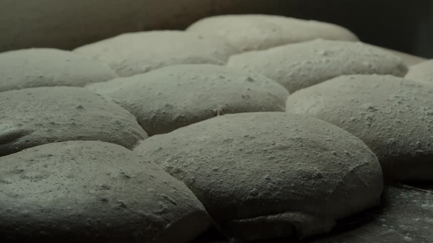 The cook removes a ball of dough from a stack