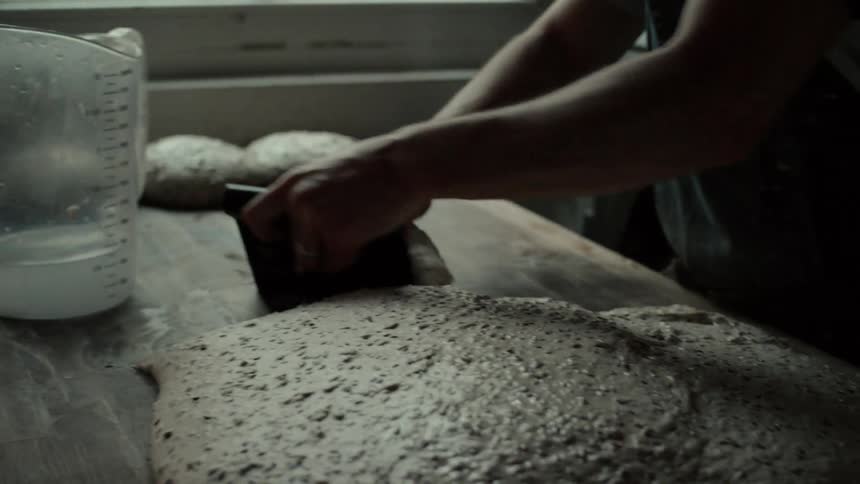 The cook removes balls of dough from the pile