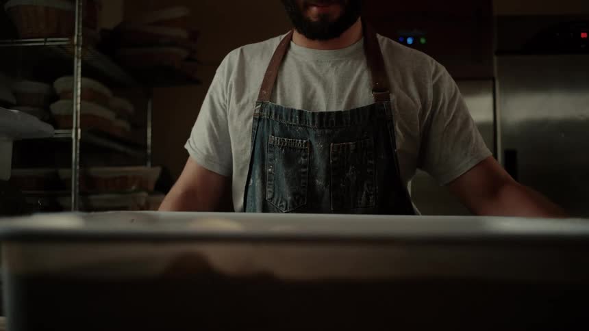 Cook in an apron removing the lid from a jar