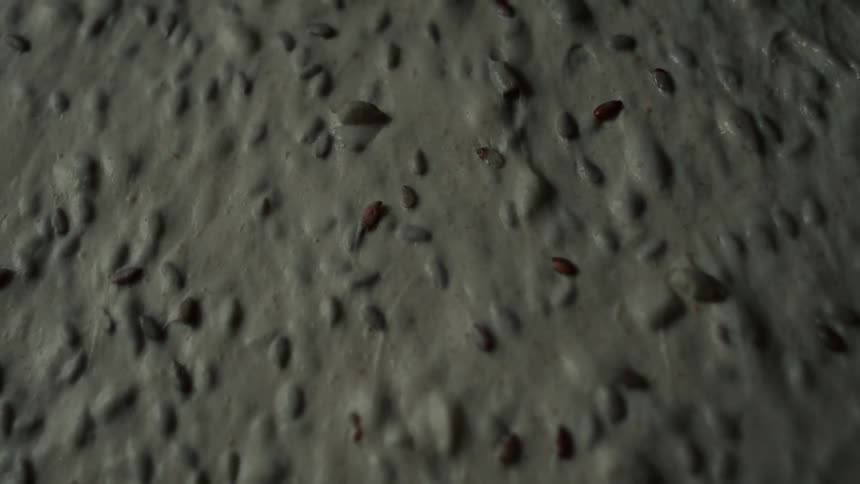 A molded piece of dough slowly sliding across the surface it rests on
