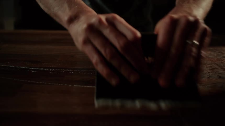 The man is cleaning the wooden table in the restaurant