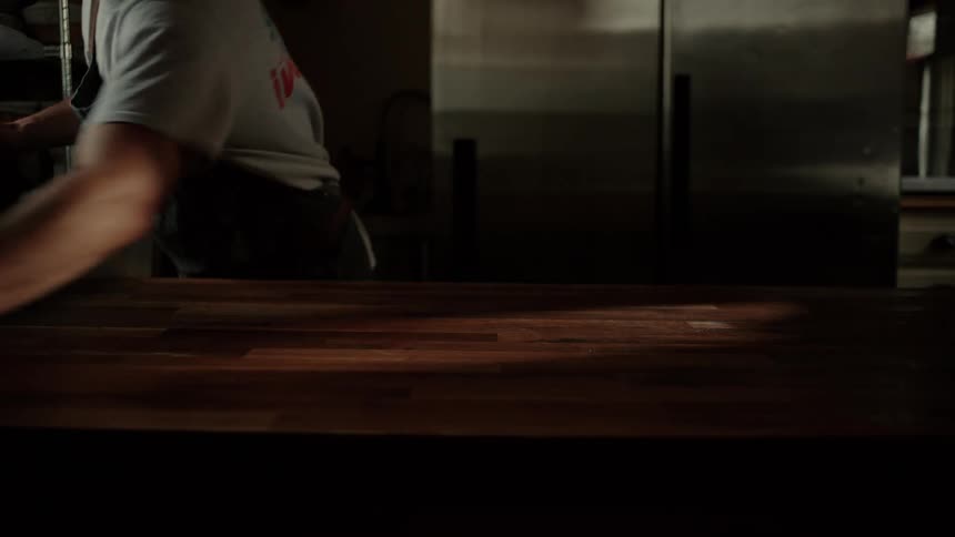 Man wipes a table clean in a restaurant kitchen and walks away