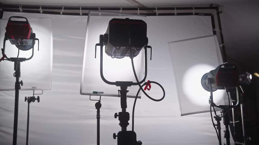 Studio lights mounted on stands with diffusers in front of a white backdrop