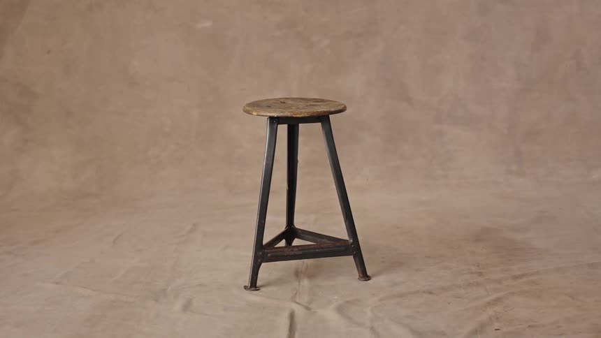 Wooden stool with a metal base positioned in a studio with a neutral backdrop