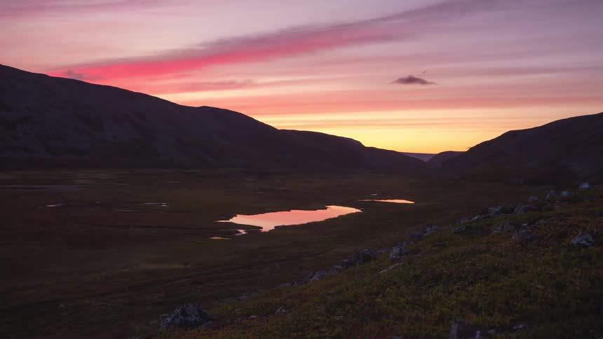 Clouds reflect in a pond at the foot of mountains