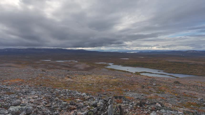 Rocks on a hill overlooking the river with mountains in the distance under a cloudy sky