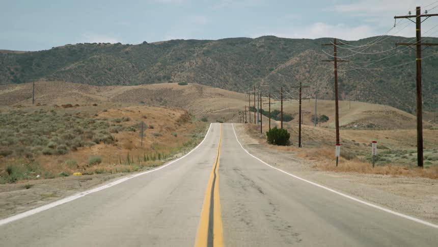 Power lines stand erect next to a desert road
