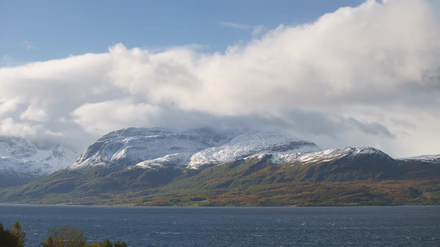A time lapse of clouds over a mountain range covered in snow