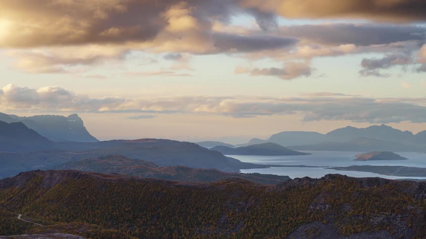 A highangle timelapse shows clouds drifting over a vast landscape of layered mountains and islands