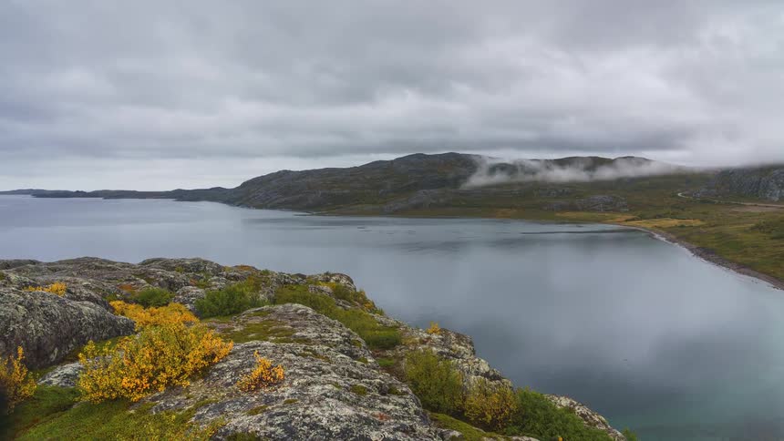 Mountains along the coast as clouds reflect on the water as they move overhead