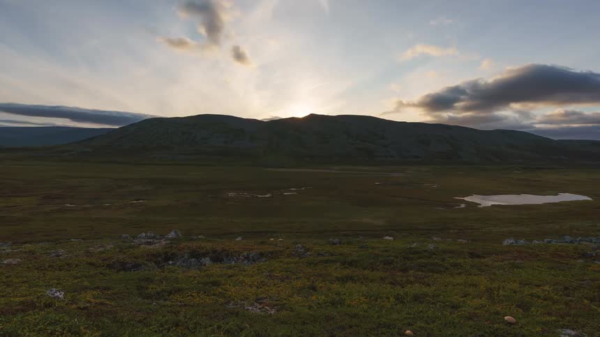 Day turning to evening in the wilderness with a surrounding mountain range in the background as the sunlight slowly fades away