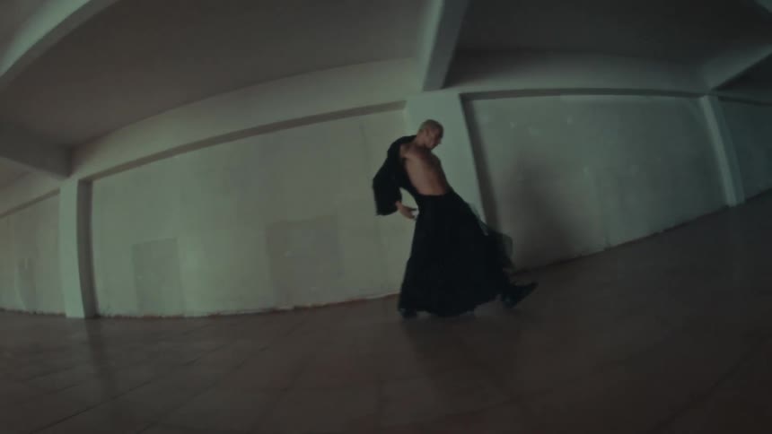 Person dances in an empty indoor space with columns and lightcolored walls