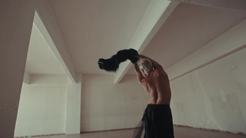 Man holding a coat and dancing in a white room