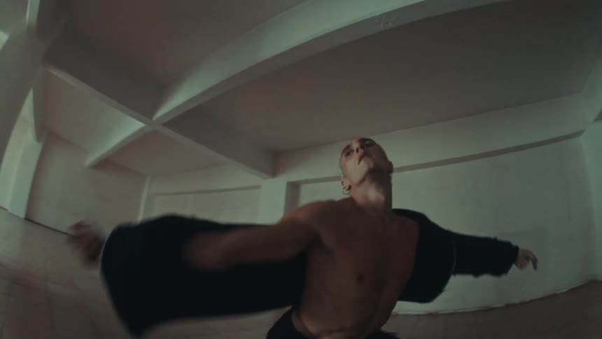 Man dancing in a room holding a black coat