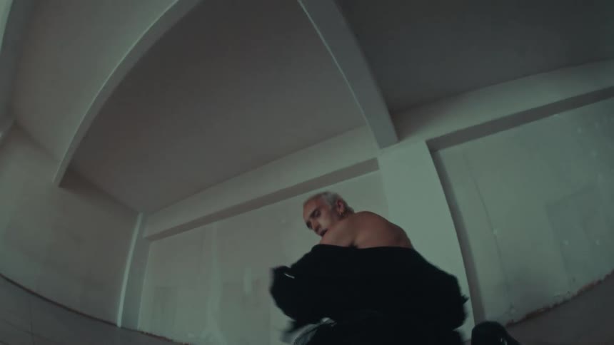 A man performs an expressive contemporary dance in a minimalist empty room