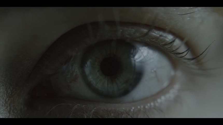 An extreme closeup of a human eye opening with detailed iris texture and sharp eyelashes