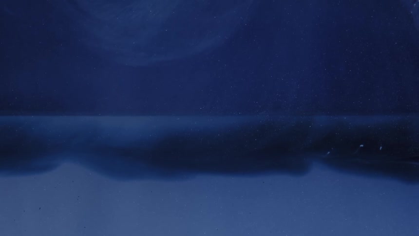 Blue ink slowly disperses in clear liquid forming fluid layers