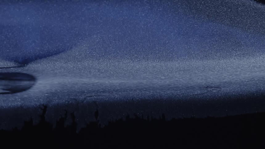 Heavy liquid flowing through a dark environment its movement thick and slow catching faint glimmers of light as it shifts through the shadows