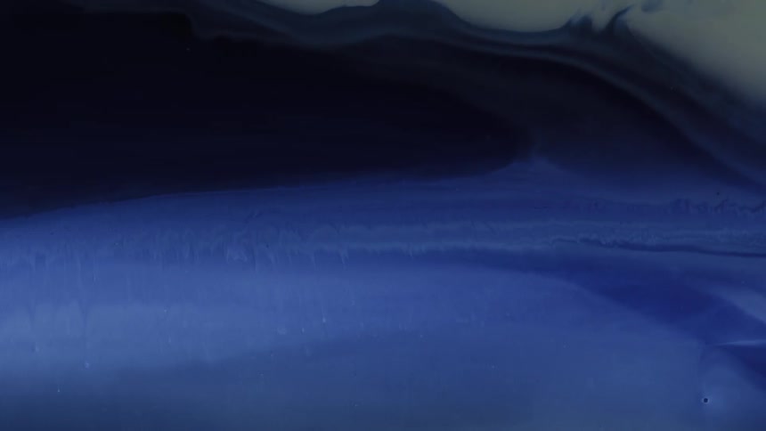 Blue and white liquids swirl together in a slow fluid motion