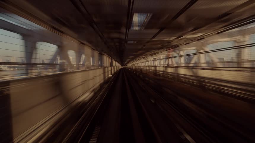 Elevated tracks follow a curve over an urban area with buildings in the background under low sunlight