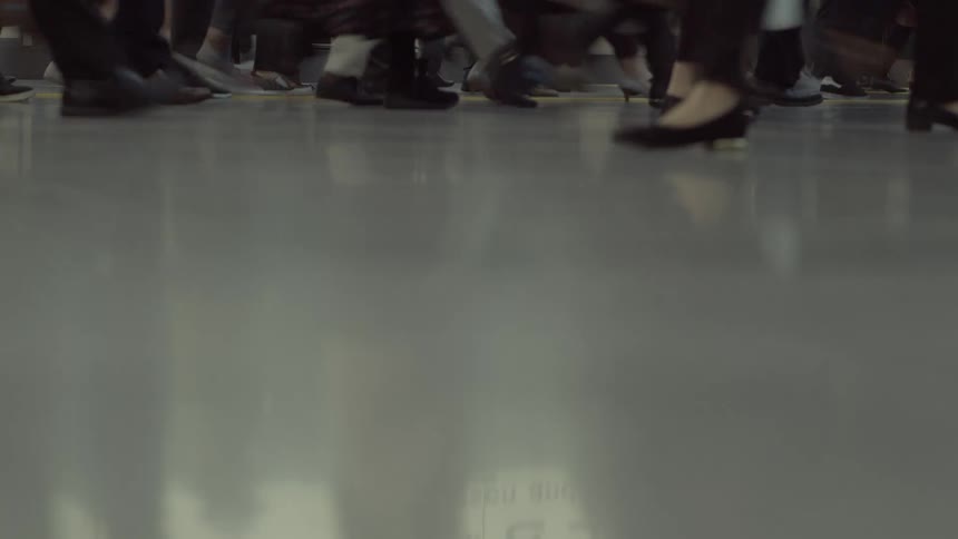 Crowd of pedestrians walks across the shiny floor in a building