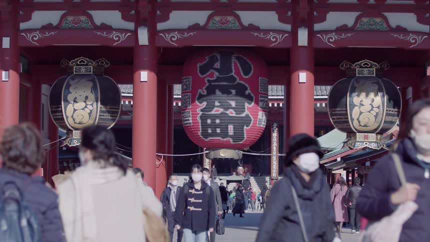 People walk towards and away from a site with east asian decorations