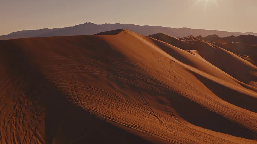The bright sun shines on the large sand dunes