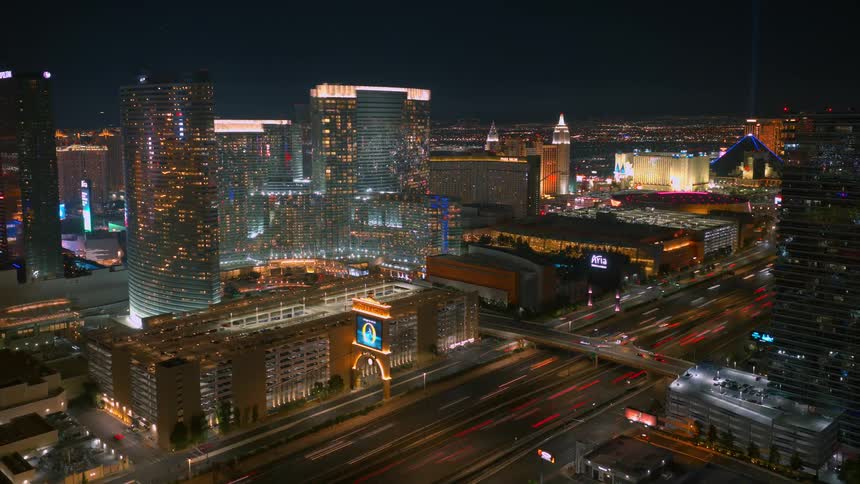 A highangle timelapse captures the Las Vegas skyline at night with blurred traffic moving along the interstate while illuminated hotels and casinos glow against the dark sky