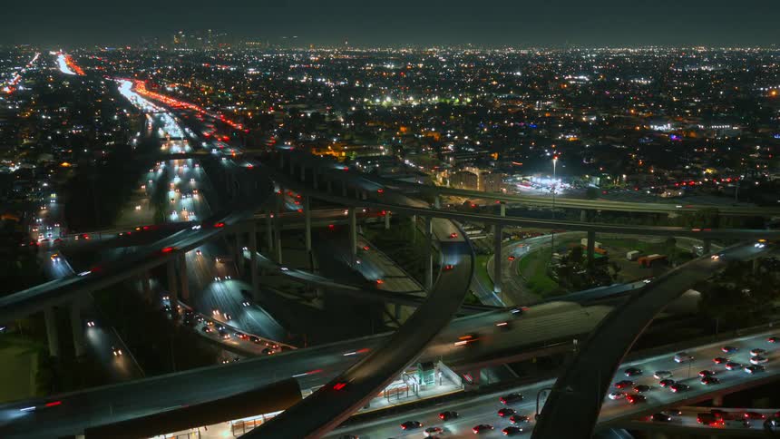 Aerial view of a busy city at night with glowing highways and flowing traffic