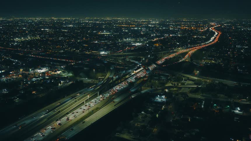 Traffic moves on a highway through a large city at night
