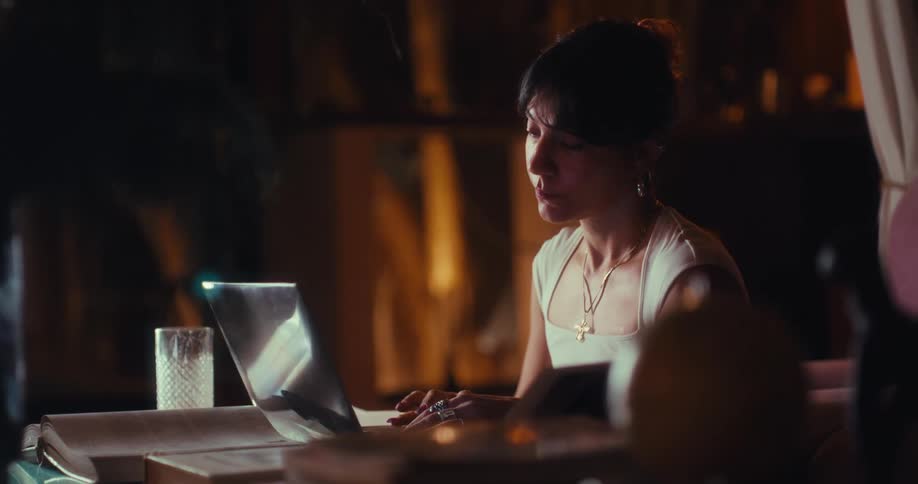 Woman sits at a table typing on a laptop computer