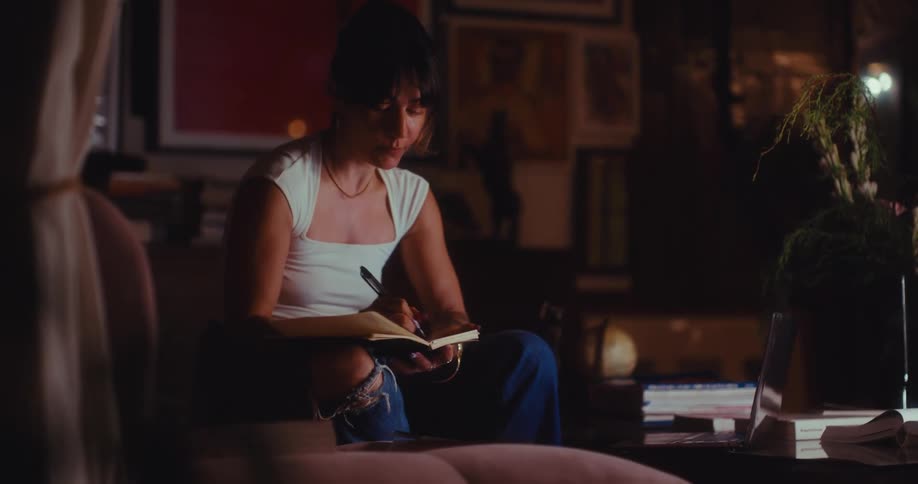 Woman sitting in a living room chair writing in a book