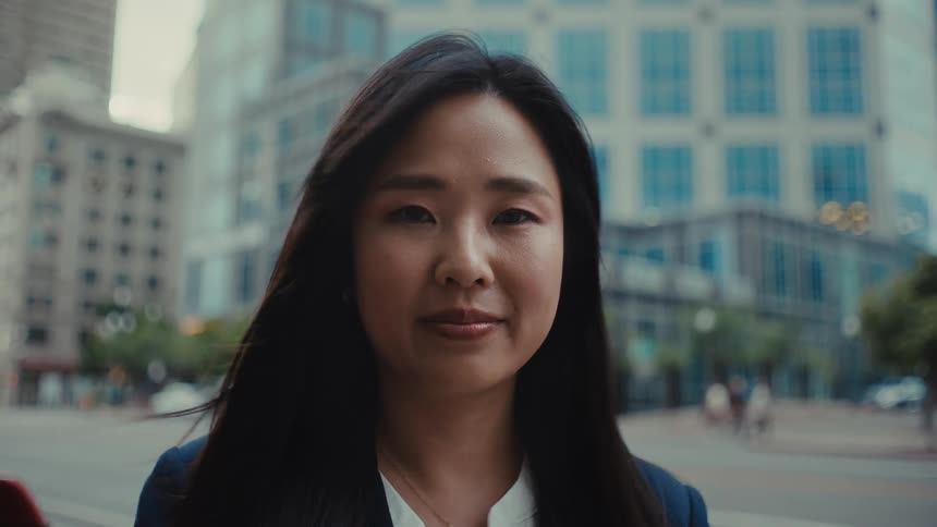 A capable professional woman stands with confidence in the city