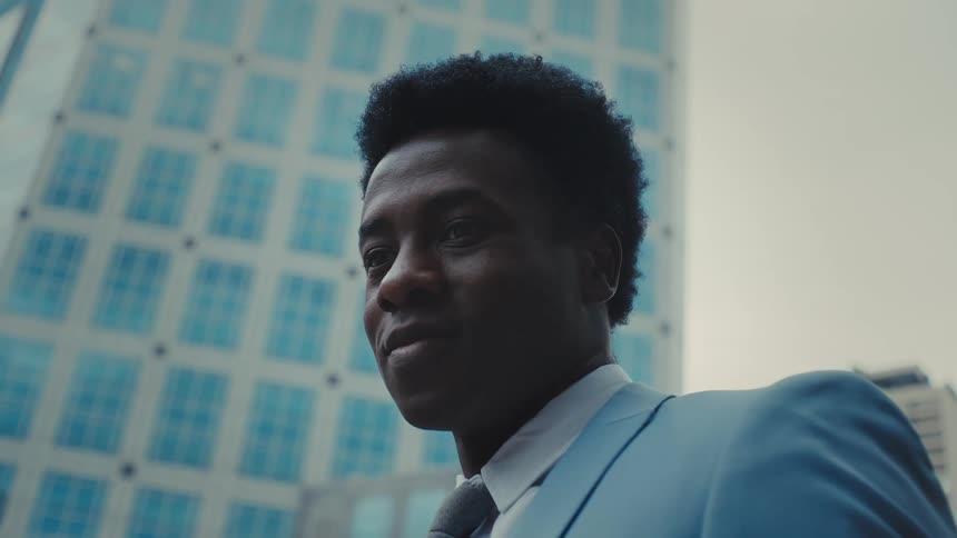 Man in a suit in an outdoor space with buildings in the background