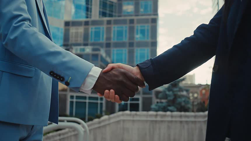 Two men in suits shake hands