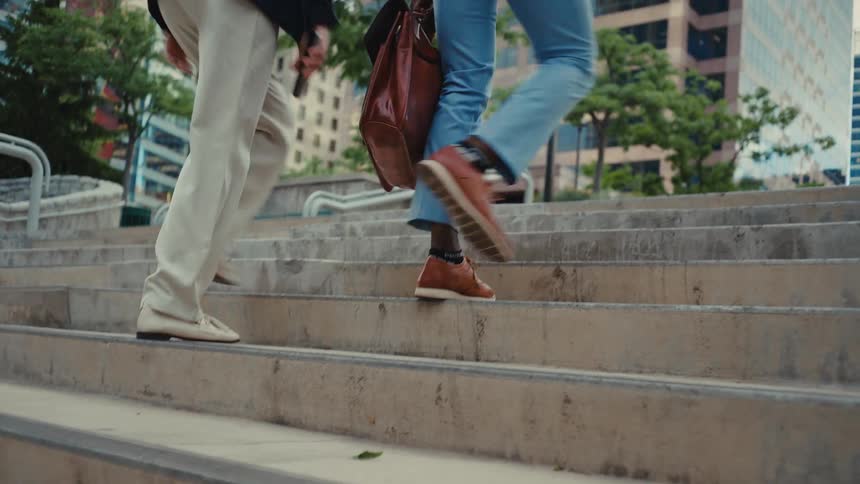 A couple is walking up outdoor stairs in a downtown area of a city