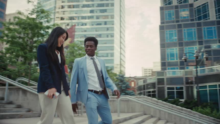 Two business colleagues talk and laugh while walking down city stairs