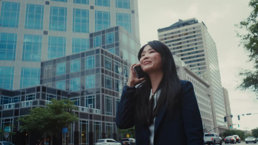 A woman steps out of her car onto a busy city street while engaged in a phone conversation