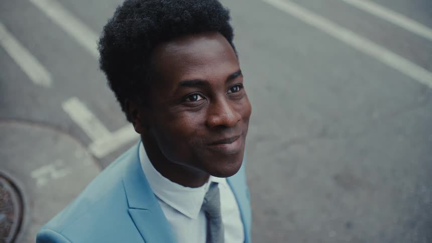 Man in suit looks up and smiles confidently
