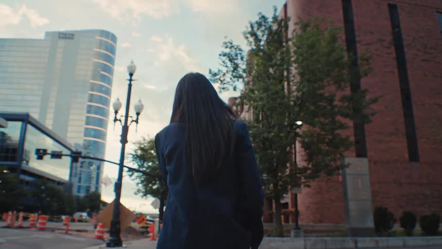 Woman walking backwards in a blazer through the city