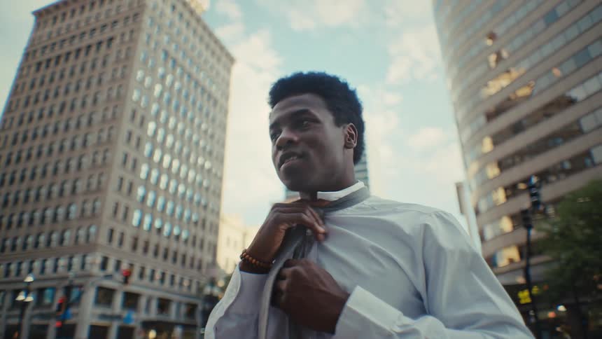The man is adjusting his neck tie outside in the city